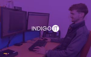 An INDIGO IT engineer at a desk with two monitors and a desk phone