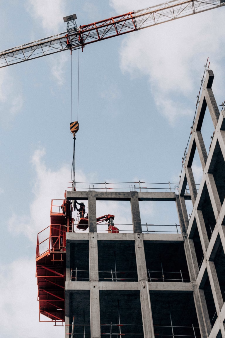 A crane lifting materials onto a concrete building frame