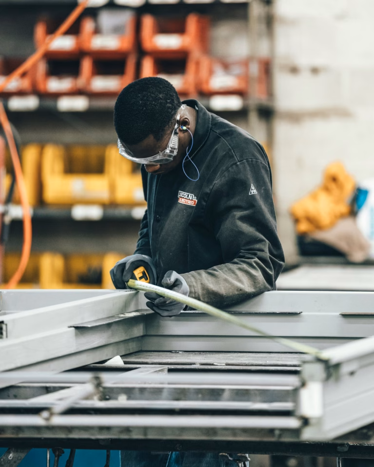 An engineer measuring a metal frame in a workshop