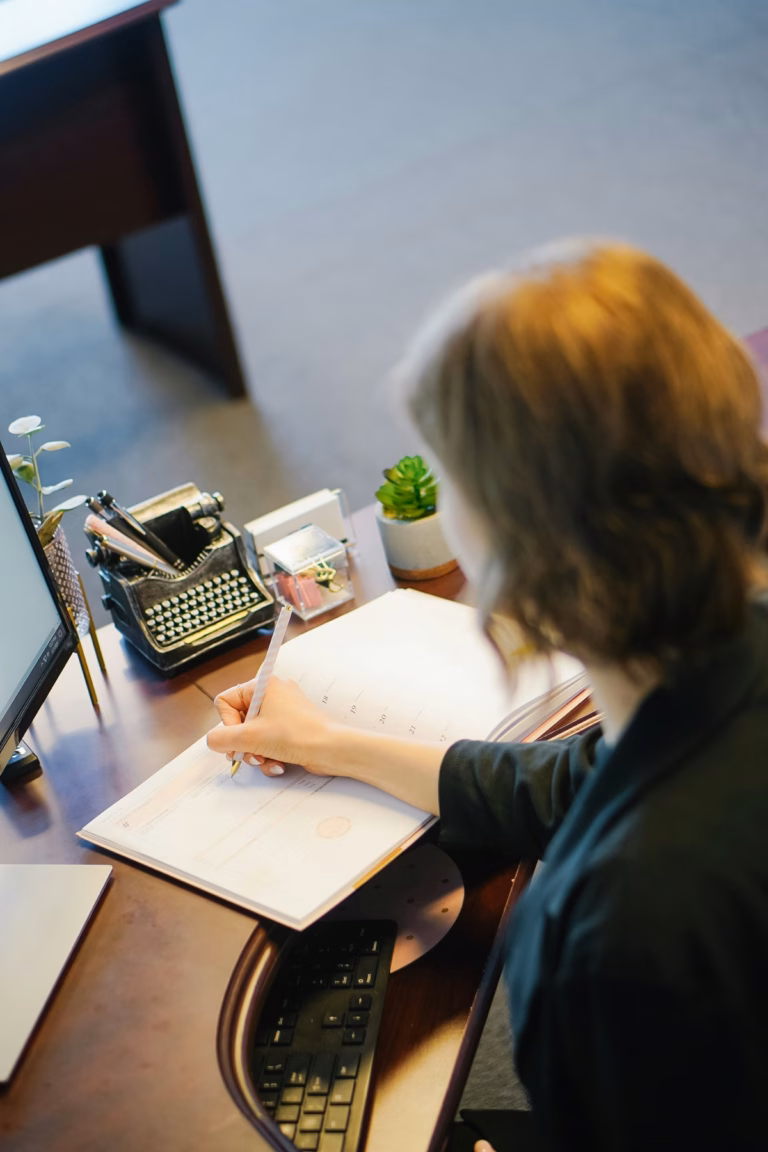 A professional writing notes at an office desk